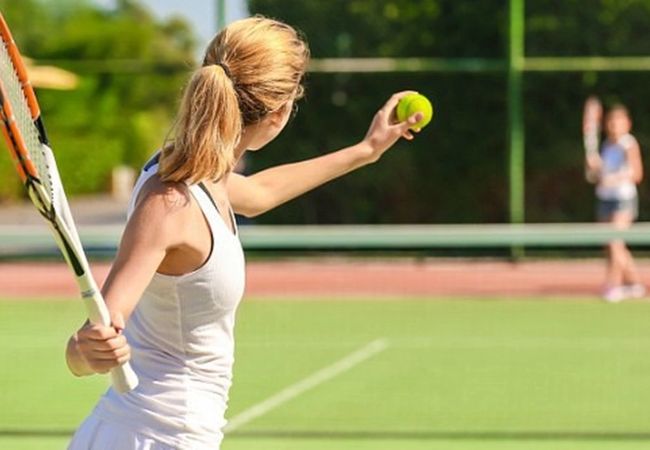 Người chơi đang cầm vợt tennis thực hiện cú giao bóng