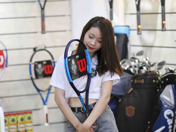 Người chơi thử vợt tại shop thể thao để chọn mua vợt tennis phù hợp.